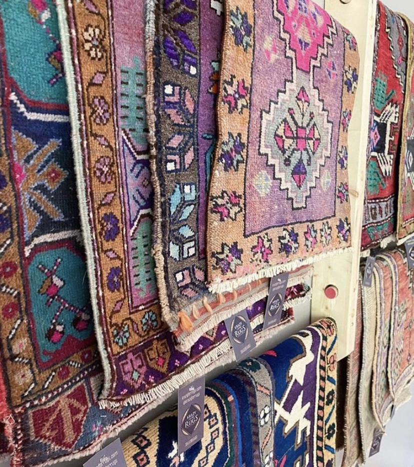 angled wall display featuring of a variety of multi-colored persian and vintage rugs